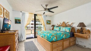 Un dormitorio con cama, ventilador de techo, televisor y balcón.
