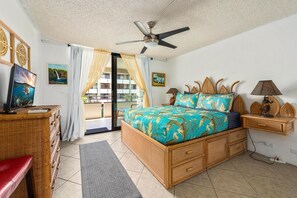 Ein Schlafzimmer mit einem Bett, einem Deckenventilator, einem Fernseher und einem Balkon.