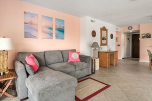 Ein Wohnzimmer mit grauem Sofa, einem rot-weißen Teppich und einem Holztisch.
