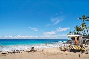 Ein Strand mit einem Rettungsturm, blauem Himmel und ruhiger See.