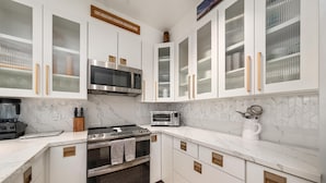 A modern kitchen with white cabinetry, a built-in microwave, a toaster, and an oven. - Big Island Waikoloa Colony Villas 2303 2 Bedroom Condo (Waikoloa)