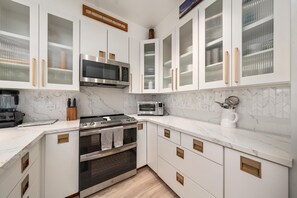 Eine moderne Küche mit weißen Schränken, einer eingebauten Mikrowelle, einem Toaster und einem Backofen.