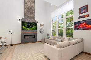 Ein modernes Wohnzimmer mit Kamin, großem Fernseher und einer Couch.