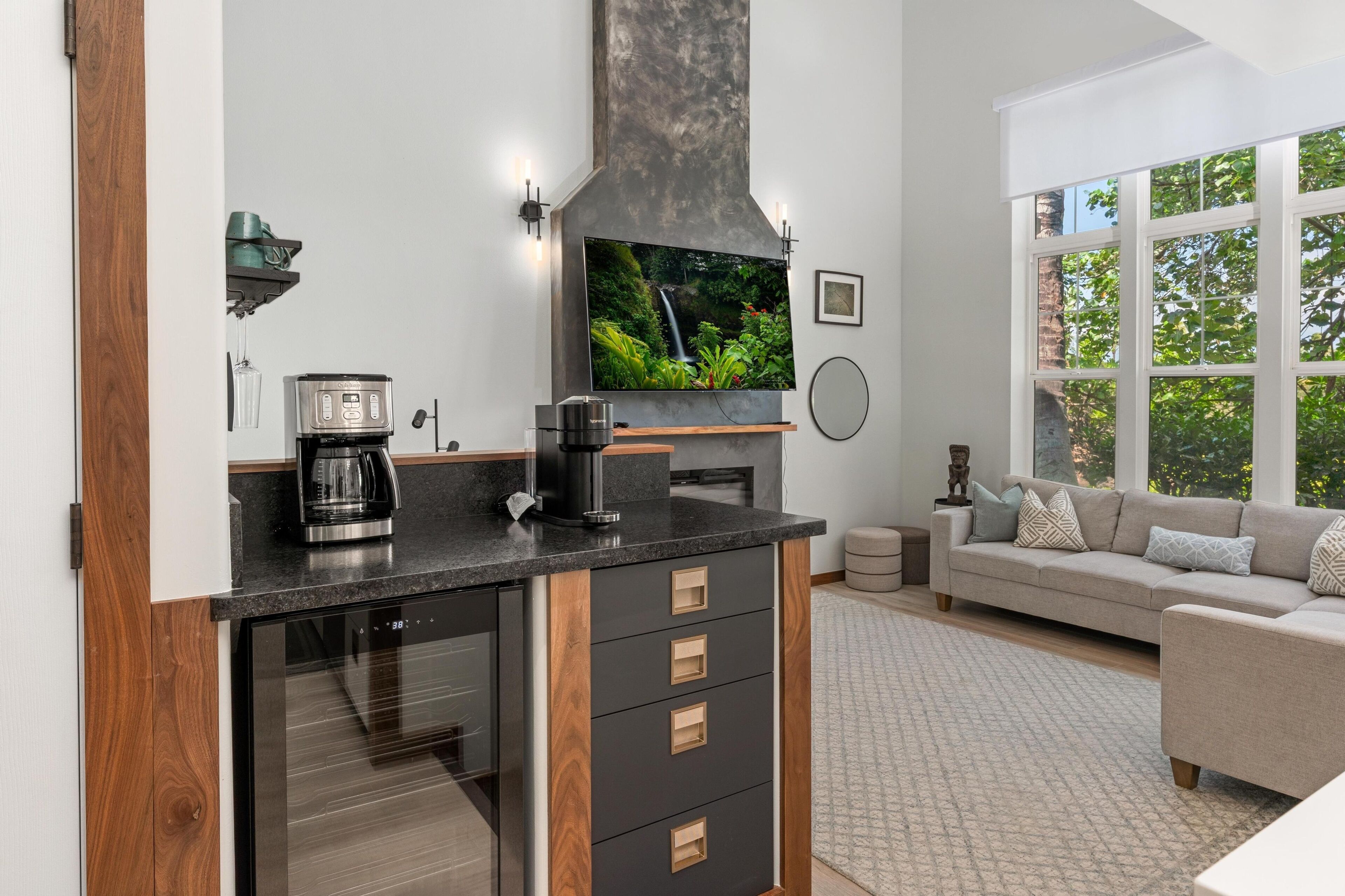 A modern kitchen with a coffee maker, espresso machine, and a large flat-screen TV.