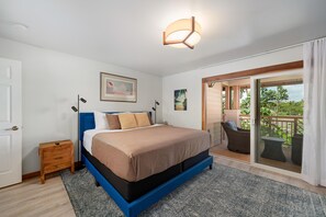 A bedroom with a bed, a nightstand, a framed picture, and a balcony with a view. - Big Island Waikoloa Colony Villas 2303 2 Bedroom Condo (Waikoloa)
