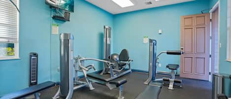 A gym with exercise equipment, a television, and a door.