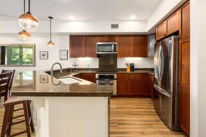 Eine moderne Küche mit Holzschränken, Edelstahlgeräten und einer Granit-Arbeitsplatte.