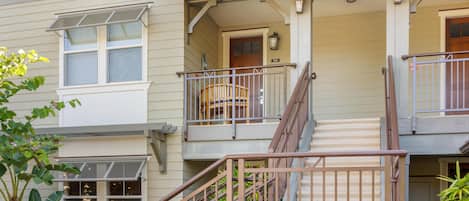 A multi-story residential building with a covered porch, a staircase, and a small balcony.