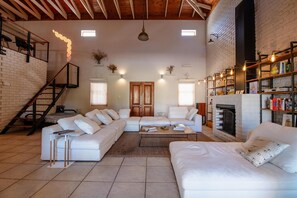 A spacious living room with a white sectional sofa, a fireplace, and a staircase leading to an upper level. - Spacious 3-bedroom home in Stellenbosch (Stellenbosch)