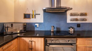 A modern kitchen with a stainless steel range hood, a microwave, a kettle, and a spice rack. - Spacious 3-bedroom home in Stellenbosch (Stellenbosch)