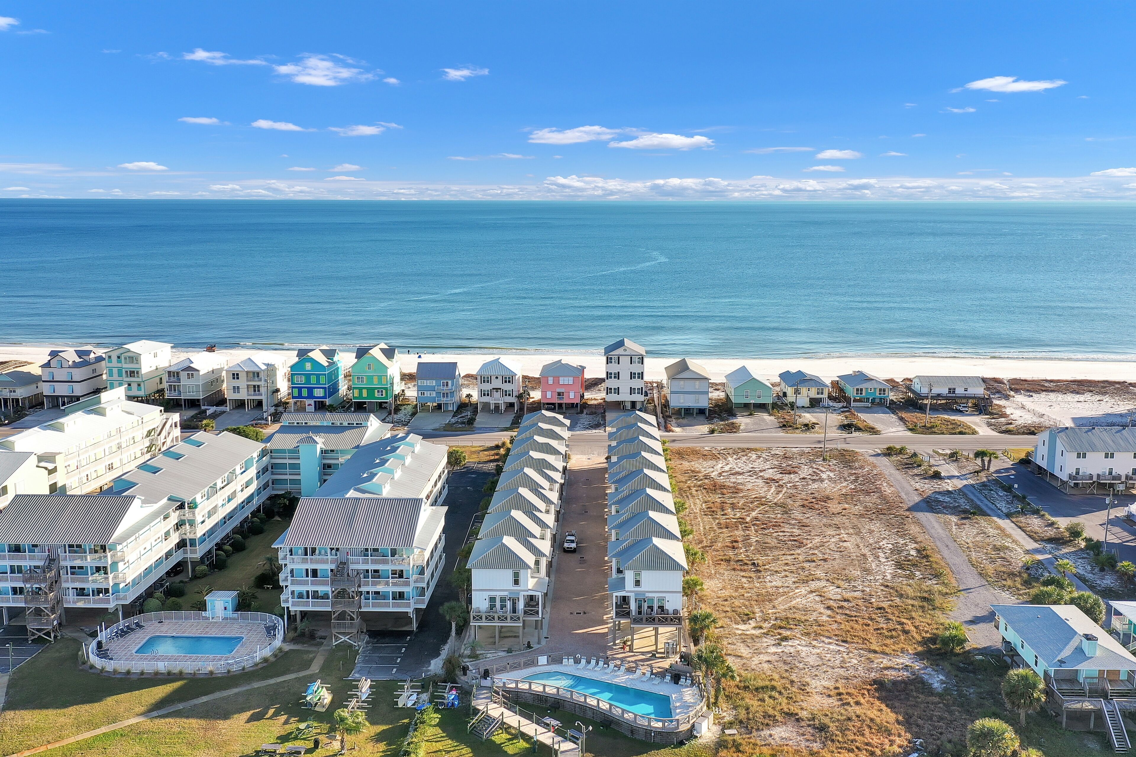 A coastal hotel with multiple buildings, a swimming pool, and a beach view.