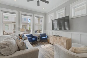 A spacious living room with a large flat-screen TV mounted on the wall, a comfortable sofa set, and a wooden coffee table. - Cottages At Lagoon Pass D 2 Bedroom Home (Gulf Shores)
