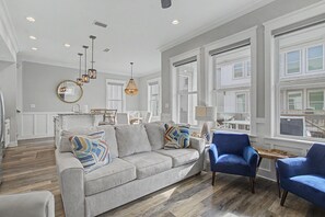 Ein geräumiges Wohnzimmer mit grauem Sofa, blauen Sessel und Holzboden.