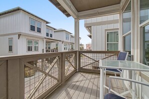 Ein Balkon mit Tisch und Stühlen, der auf eine Reihung weißer Häuser mit zahlreichen Fenstern blickt.