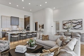 A modern living room with a sofa, coffee table, and a kitchen area with a bar. - Mtn Retreat w/ Hot Tub, Game Room & Lake Views (Heber City)