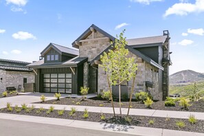 A modern two-story house with a stone facade, a garage, and a landscaped front yard with young trees. - Mtn Retreat w/ Hot Tub, Game Room & Lake Views (Heber City)