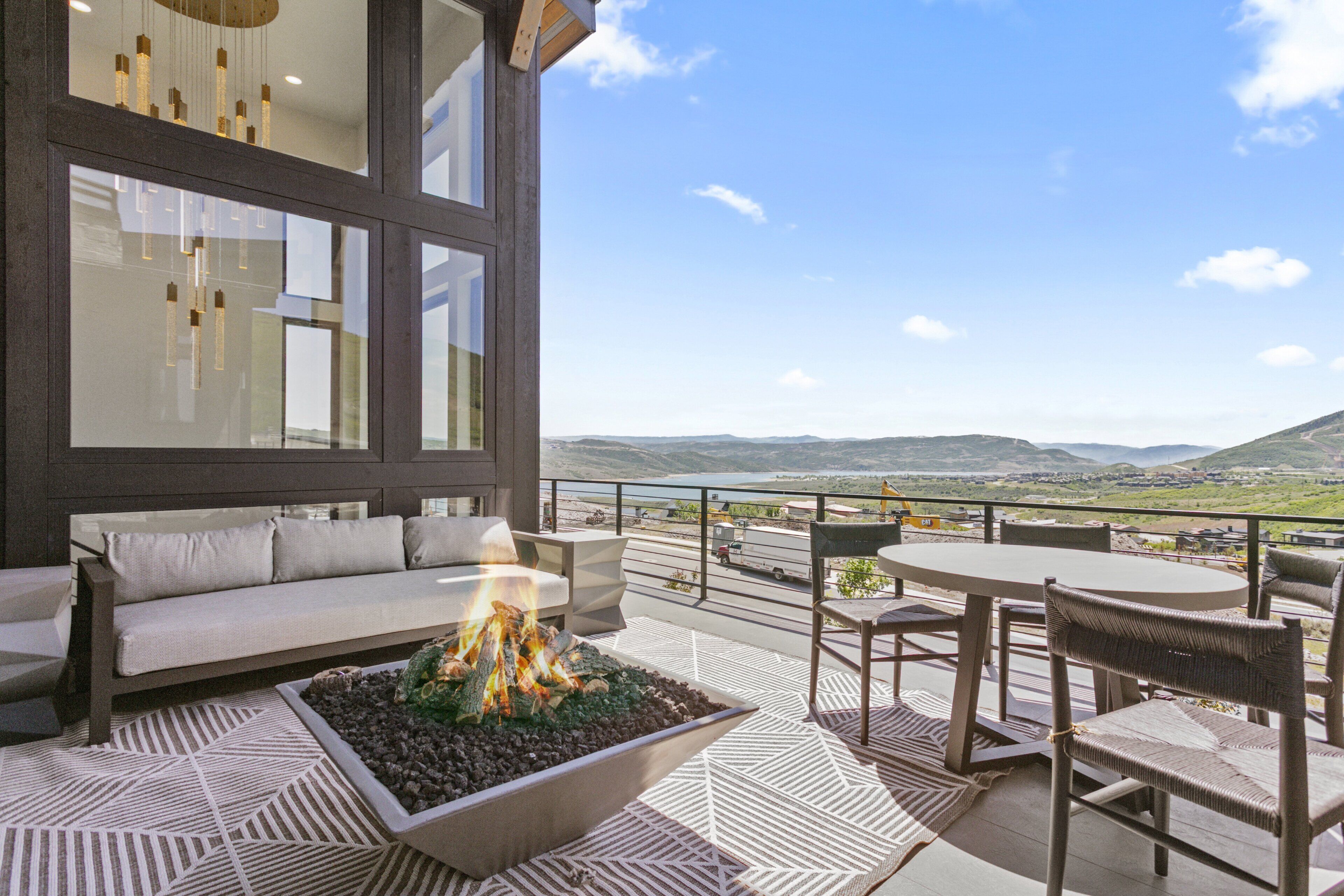 Un área de estar exterior moderna con una chimenea, un sofá y vistas al paisaje.