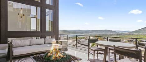 Un área de estar exterior moderna con una chimenea, un sofá y vistas al paisaje.