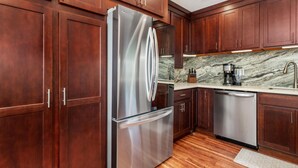 A modern kitchen with wooden cabinets, stainless steel appliances, and a marble backsplash. - Big Island Keauhou Punahele C202 2 Bedroom Condo (Kailua-Kona)
