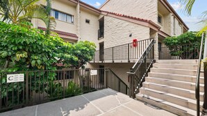 A residential building with a stone facade, a gated entrance, and a staircase leading to the entrance. - Big Island Keauhou Punahele C202 2 Bedroom Condo (Kailua-Kona)