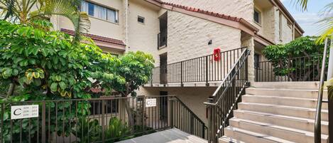 A residential building with a stone facade, a gated entrance, and a staircase leading to the entrance.