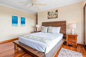 A bedroom with a bed, bedside tables, a ceiling fan, and artwork on the walls. - Big Island Keauhou Punahele C202 2 Bedroom Condo (Kailua-Kona)