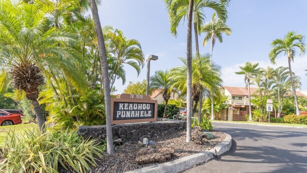 A sign for 'Keauhou Punahole' with a street view, palm trees, and a building in the background. - Big Island Keauhou Punahele C202 2 Bedroom Condo (Kailua-Kona)