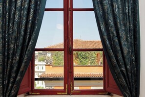 A window with a view of a building with a tiled roof and a balcony. - Colosseum Grand Luxury Residence for 14 Guests (Roma)
