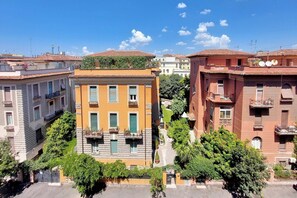 A row of buildings with balconies, a central building with a green awning, and a clear blue sky. - Colosseum Grand Luxury Residence for 14 Guests (Roma)