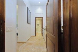A hallway with a wooden door, a framed picture on the wall, and a tiled floor. - Colosseum Grand Luxury Residence for 14 Guests (Roma)