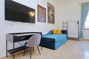 A modern room with a flat-screen TV, a desk, a blue sofa with yellow cushions, and a metal ladder. - Colosseum Grand Luxury Residence for 14 Guests (Roma)