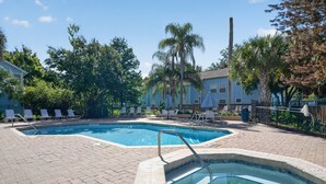 Un espace piscine comprenant deux piscines, des chaises longues et un jacuzzi.