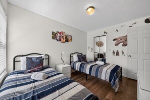 A bedroom with two beds, a bedside table with a lamp, and Star Wars-themed decorations on the walls. - "Your Happy Place" Close To All The Magic! 3 Bedroom Condo (Kissimmee)