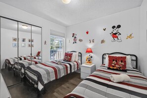 A hotel room with two beds, a large mirror, and Mickey Mouse decorations on the wall. - your Happy Place Close To All The Magic! 3 Bedroom Condo (Kissimmee)