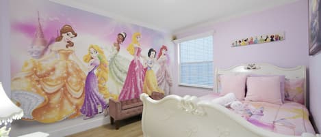 Une chambre avec une grande fresque murale représentant les princesses Disney, un lit avec une literie rose et une fenêtre avec des stores.