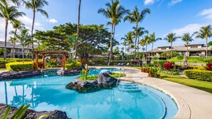 A resort pool with clear blue water, surrounded by tropical vegetation and palm trees. - Golf Villas At Mauna Lani J23 2 Bedroom Condo (Kamuela)