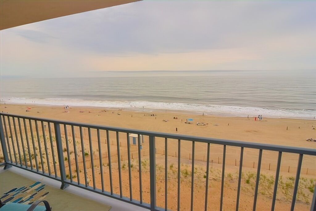 Blick auf einen Strand vom Balkon mit Geländer, feiner Sand und das Meer.