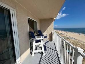 A balcony with a view of the beach, white chairs, and a railing. - OCEAN FRONT CONDO.  ENJOY YOUR MORNING COFFEE SITTING ON YOUR PRIVATE BALCONY WATCHING THE SUNRISE. (Rehoboth Beach)