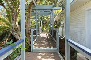 A covered wooden walkway with a metal railing, surrounded by trees and vegetation. - Single-story Navarre home sleeping 9 across 4 bedrooms, just minutes from sugar-white Navarre Beach. Full kitchen, in-unit laundry, workspace, and a beach bag stocked with towels & life jackets. Perfect for an easy Gulf Coast family escape! (Navarre)