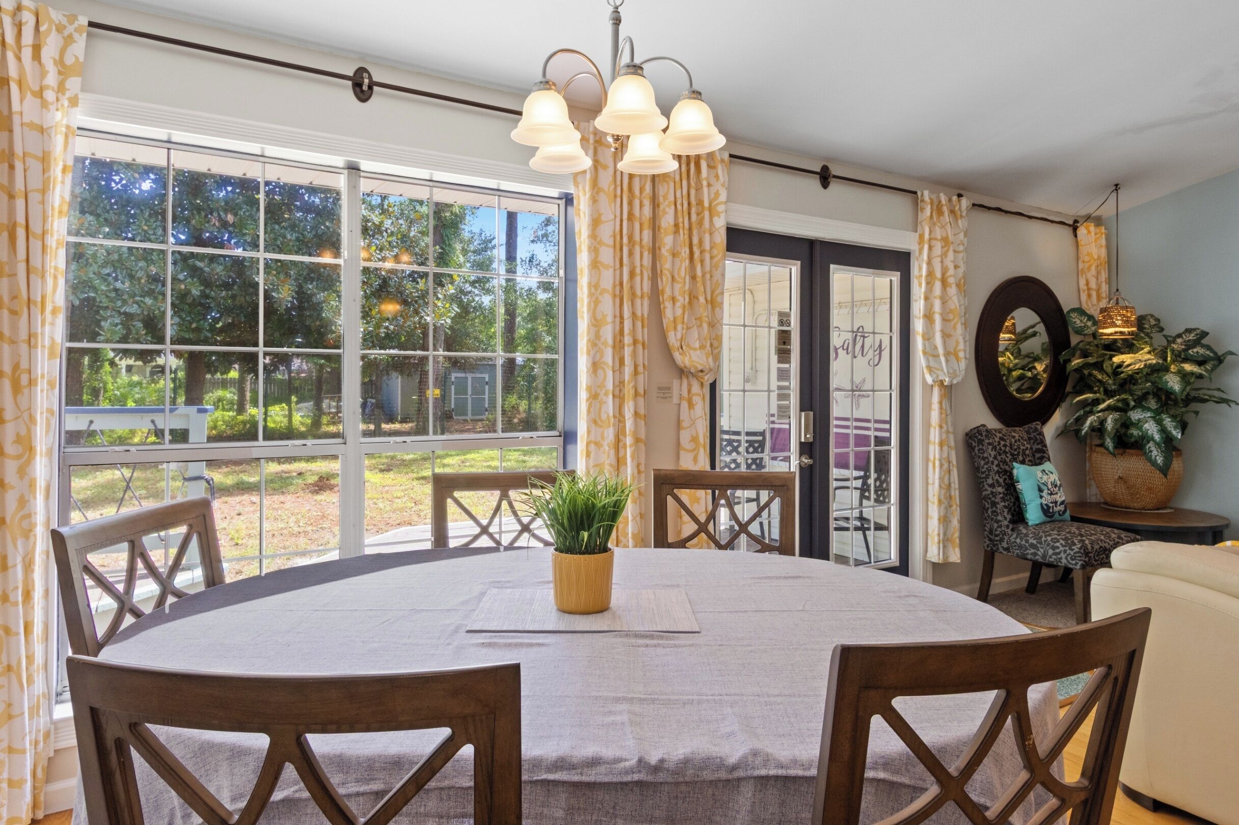 A dining area with a round table, chairs, and a potted plant.