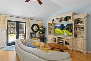 A living room with a sofa, television, and wooden cabinets. - Single-story Navarre home sleeping 9 across 4 bedrooms, just minutes from sugar-white Navarre Beach. Full kitchen, in-unit laundry, workspace, and a beach bag stocked with towels & life jackets. Perfect for an easy Gulf Coast family escape! (Navarre)