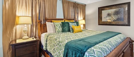 A bedroom with a bed, nightstands, a ceiling fan, and a framed picture on the wall.