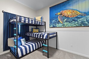 Un lit superposé avec une literie à rayures et une fresque représentant une tortue de mer sur le mur.