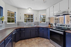 A modern kitchen with dark cabinetry, a built-in oven, and a large window. - Single-story Navarre home sleeping 9 across 4 bedrooms, just minutes from sugar-white Navarre Beach. Full kitchen, in-unit laundry, workspace, and a beach bag stocked with towels & life jackets. Perfect for an easy Gulf Coast family escape! (Navarre)