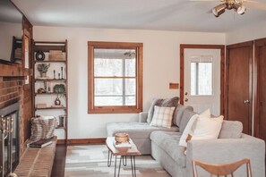 Un salon chaleureux avec une cheminée, un canapé, une table basse et une bibliothèque.