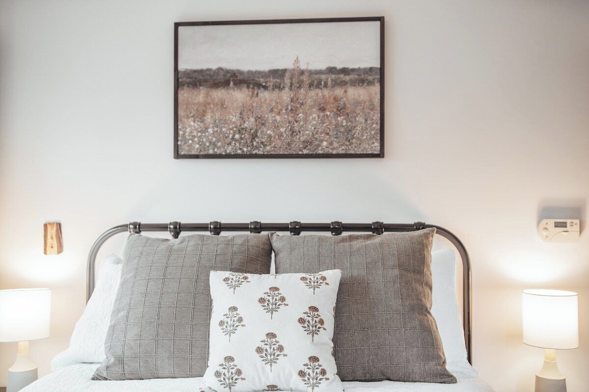 A bed with a metal headboard, two pillows, a wall-mounted picture, and bedside lamps.