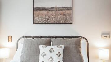 A bed with a metal headboard, two pillows, a wall-mounted picture, and bedside lamps.