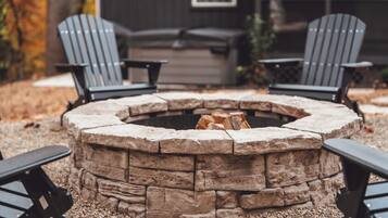 Ein Steinkamin mit vier Adirondack-Stühlen darum.
