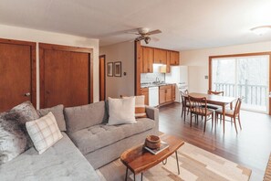 A living room with a sofa, coffee table, and dining area with chairs and a table.