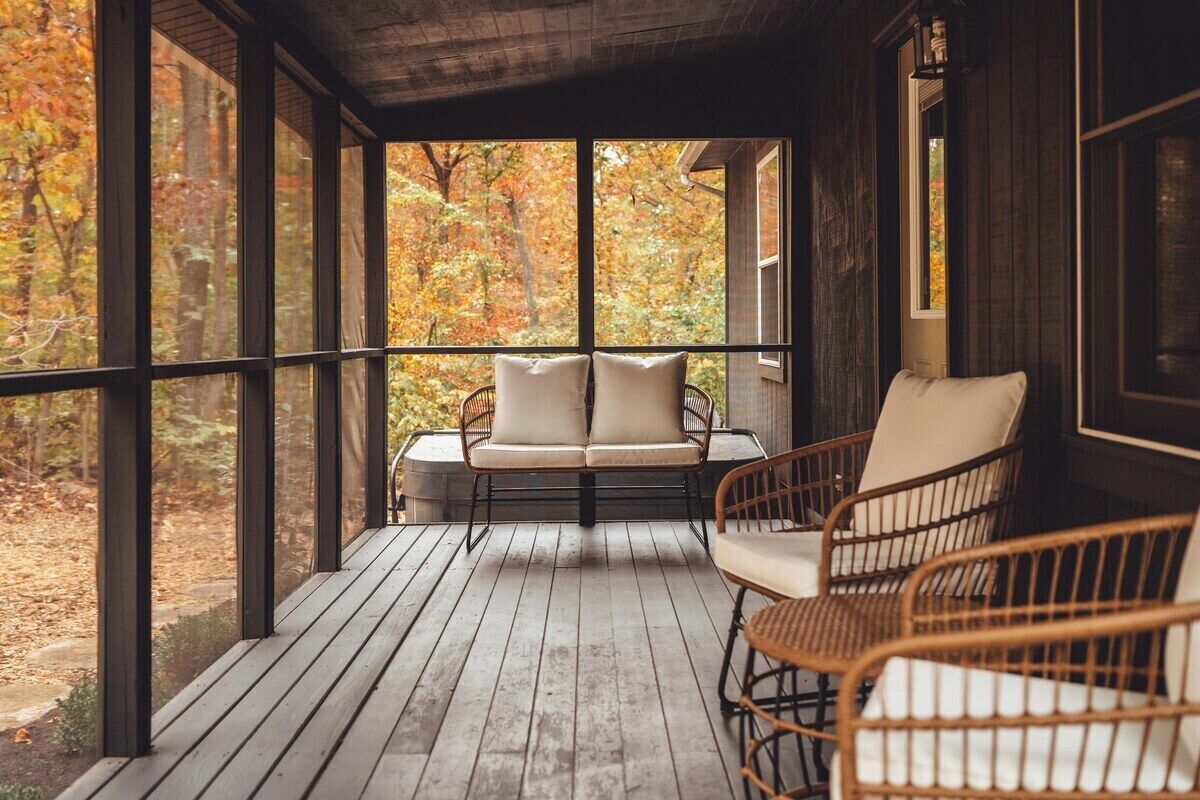 Een houten terras met rieten meubilair en uitzicht op herfstkleuren.